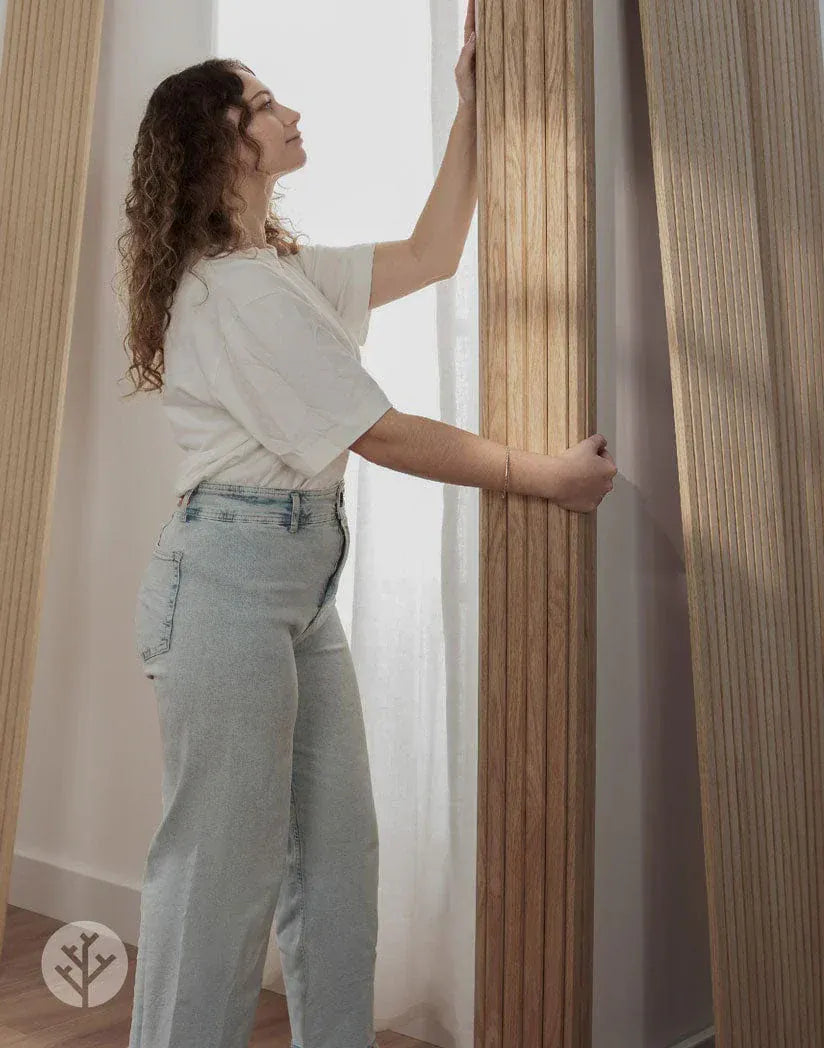Woman demonstrating Flutto panel flexibility by bending oak slat panel to show curve capability