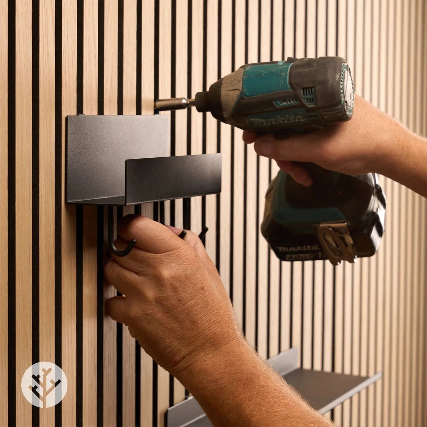 Shelf with four hooks being installed on a oak wood slat wall