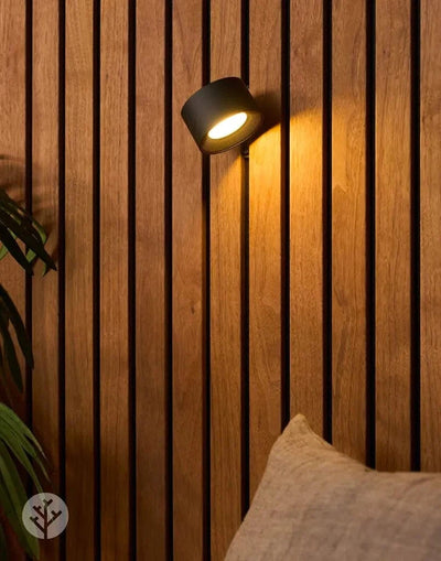 Black cylindrical Acupanel Glow beam light mounted on oak slat wall glowing warm light downward