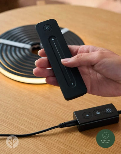 Hand pointing remote at LED-lit Acupanel wall demonstrating wireless control from distance