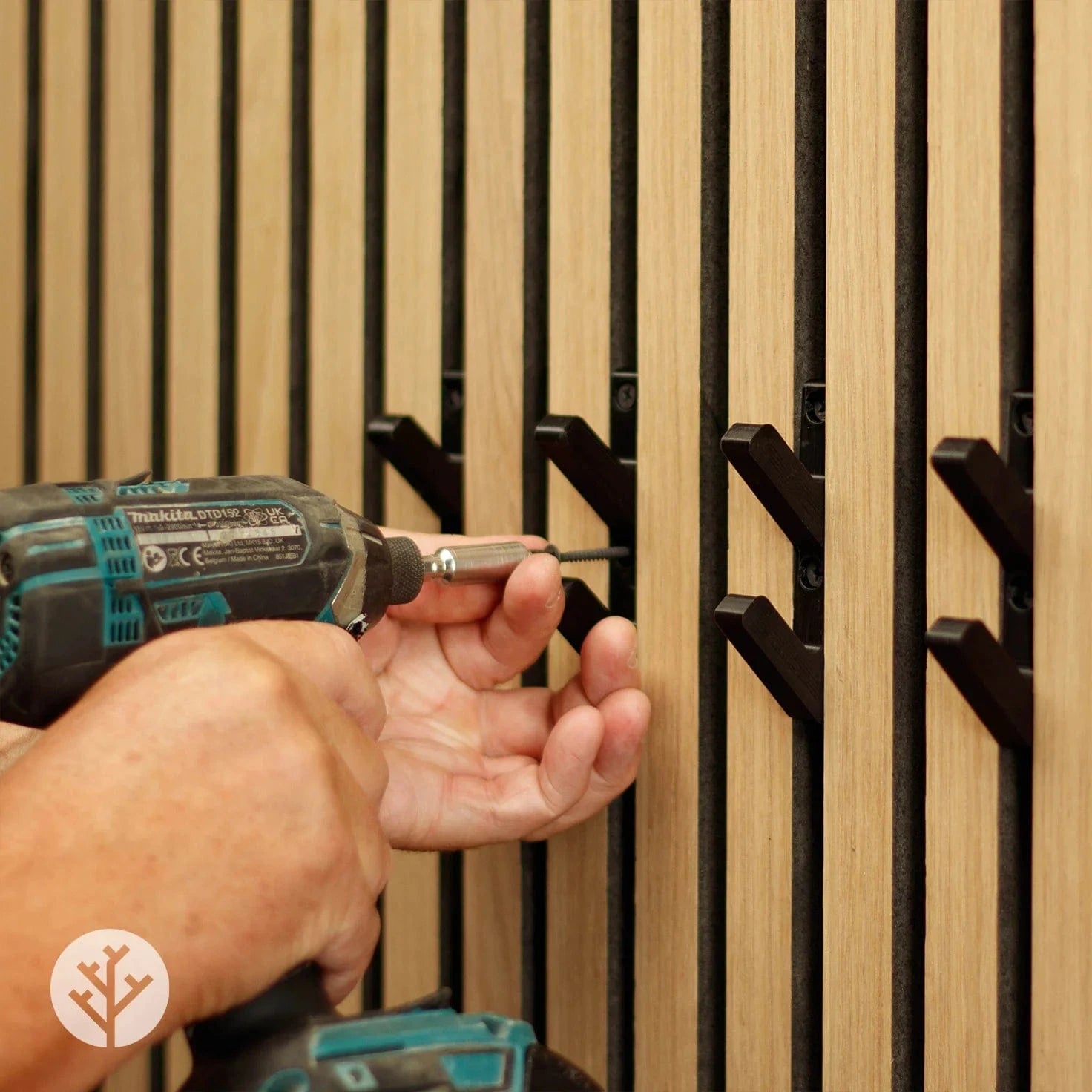 Hand using drill to install black 3D hook between Acupanel slats showing mounting process