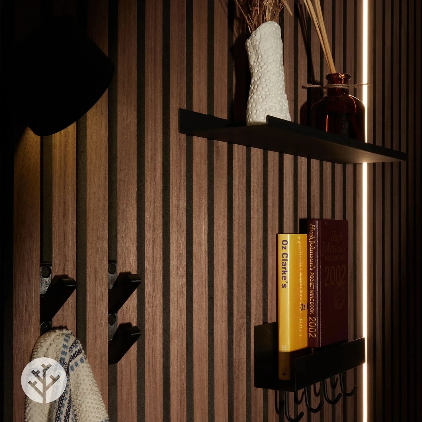 Black hooks on walnut Acupanel with coat and accessories hanging from hooks below shelf