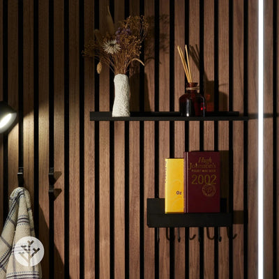 Black large ledge shelf mounted on walnut Acupanel wall with books dried flowers and reed diffuser