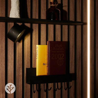 Black shelf with four hooks mounted on walnut Acupanel with books coffee cup and hanging items