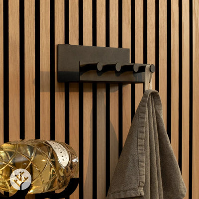 Black shelf with four pegs mounted on oak Acupanel with towel and accessories hanging below