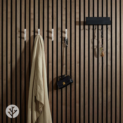 White 3D hooks installed on walnut Acupanel wall with coat bag and accessories hanging