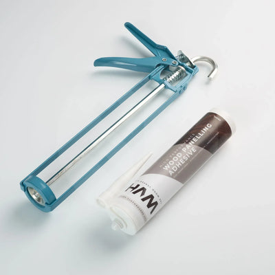 Teal caulking gun loaded with WVH branded wood panelling adhesive cartridge on white background